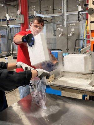 Employee's at A+ Heler's Dry Ice packaging a 10x10x2 (10 lb.) dry ice slab cut from a 50 lb. block for a customer.