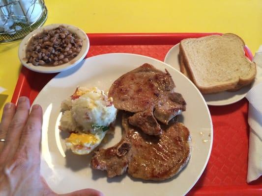 Pork chop lunch special with cheezy potatoes and peas. With side of white bread.