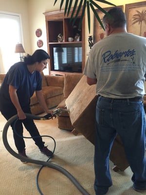 Roberto and Monica cleaning a couch