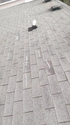 Wind damage to three tab shingles. Chalk marking the damaged shingles during an inspection.