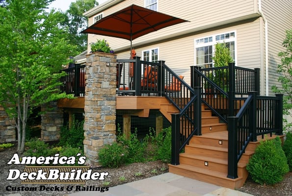 Custom stone planters and black railing blend this Jackson, New Jersey deck comfortably into its wooded surroundings.