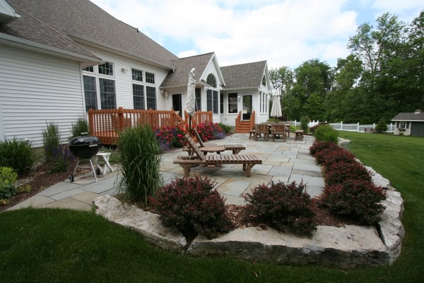 Bluestone patio with a limestone wall and new plantings