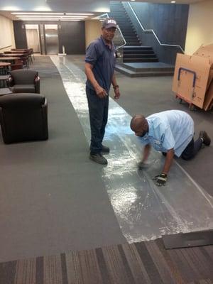 Staff at Moving Masters protecting carpet before an office move.