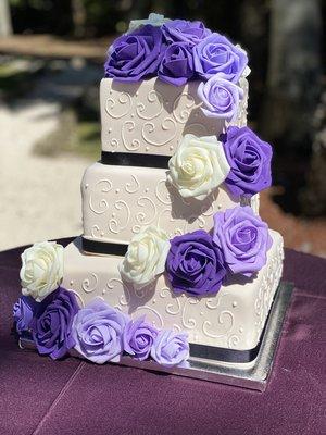 Three tiered vanilla rum and coconut wedding cake in Victorian swirl design with fondant roses