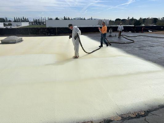 Applying polyurethane coating on roof prior to seal coating.