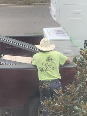 Worker standing in garden bed and wearing a branded shirt clearly indicating company.