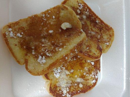 Three slices of french toast served with butter, syrup, and powdered sugar.