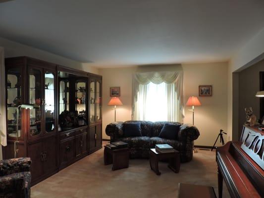 A very spacious living room has custom window treatments and plush carpeting.