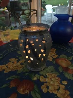 Vase on the dinner table at night. The candle flickers cast such a pretty glow through the leaf shaped cutouts.