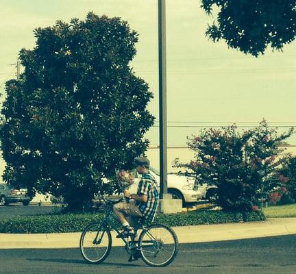 A boy rides thru the parking lot with flowers