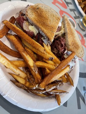 Hot pastrami and swiss sandwich with fries.