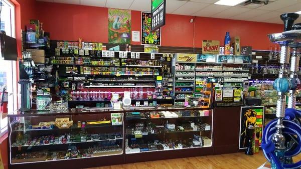 Cigarillos, Wraps, and E-liquid behind the displays. Grinders, Scales, Vaporizers, and E-cigs in the displays.