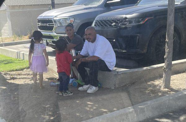 Just a family, sharing a tall boy with their lil niño out front.