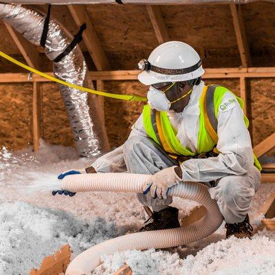 We specialize in a wide range of insulation products. Depicted is an installer putting blown-in insulation in an attic.