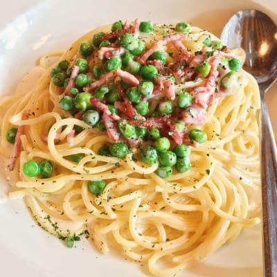 Fresh pea and prosciutto in a light cream sauce on spaghetti.