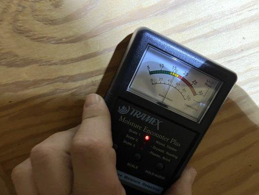 Taking a moisture reading on timbers inside of a crawl space