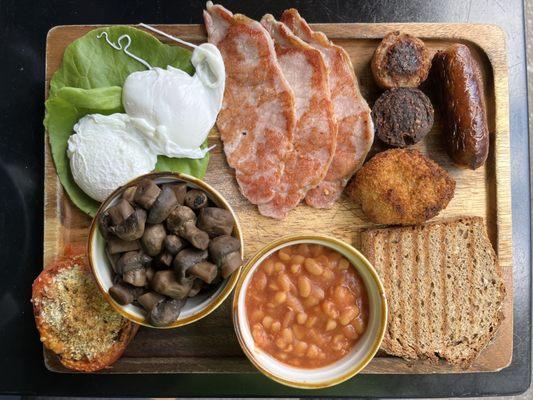 Full English Breakfast. Clockwise: poached egg, bacon, pudding, sausage, potato cake, soda bread, baked beans, mushroom, tomato