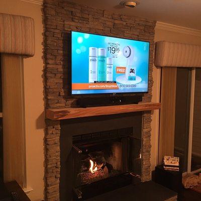 Wall Mounted TV with Soundbar on stone fireplace.