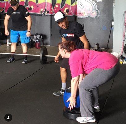 Joseph helping a member work on her form for the deadlift.