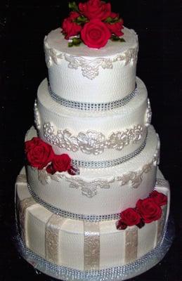 White buttercream, fondant lace and red gumpaste roses with bling ribbon borders.