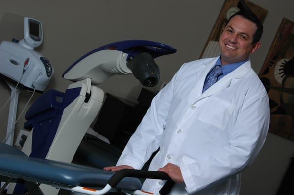  Dr. Tyce Hergert DC, the founder of Chiropractic Care Center Southlake standing beside equipment used in Cold Laser Therapy.