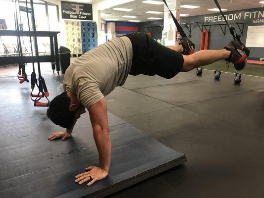 A boot camper focusing on a keeping his abs and core muscles active while engaging the TRX bands