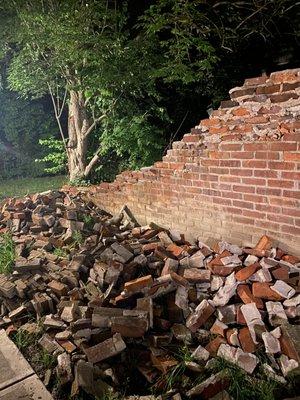 Partially collapsed (and leaning) brick wall bordering the sidewalk used to access homes in our building