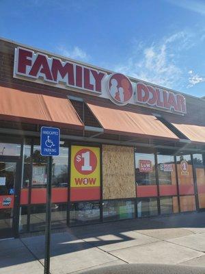 Front of store has a window boarded up.