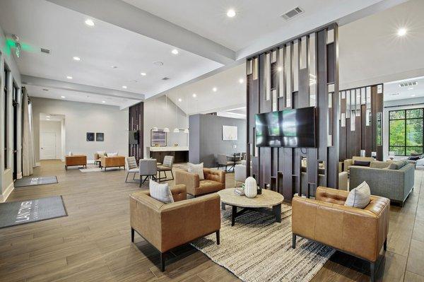 Clubhouse with modern, leather-style seating, wood-style floors, TVs, and ample natural sunlight at Lantower Garrison Park.