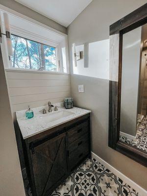 Bathroom remodel in rustic farmhouse style - New tile, shiplap accent wall, bar light sconces, new trim and wall color.