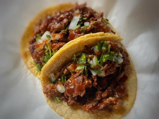 Adobada served on a Hand-Pressed Corn Tortilla with Cilantro, Onion, and our Smoky Red Sauce.