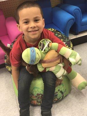 My son with a ninja turtle in a ninja turtle chair lol