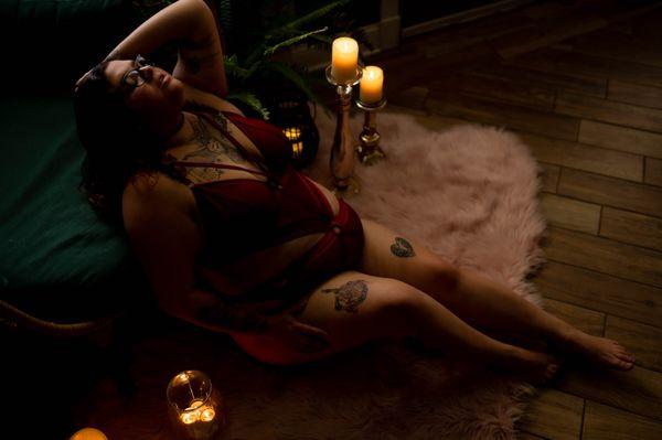 Description: A woman lounging on a pink fur rug surrounded by candles