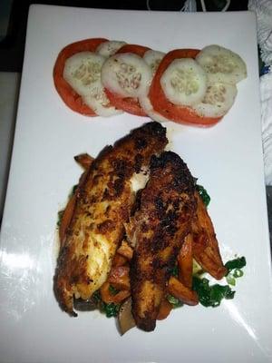 Pan seared tilapia served on a bed of sauteed spinach and mushrooms with roasted sweet potato fries and a cucumber tomato salad.