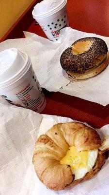 Egg and cheese on a croissant, bagel with sausage, egg and cheese and two coffees.