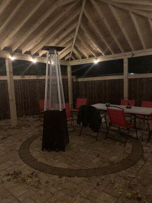 Outdoor seating area covered  with a wooden gazebo, heated and decorated in rope lights.  Very pretty.