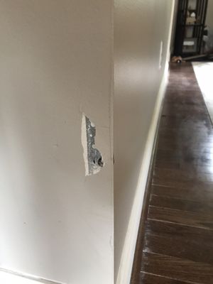 Hole left in living room wall from drill that came through from kitchen.