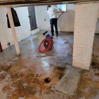 Basement flooding, guy (seller's) using squeegee to push water into sump pump drain.