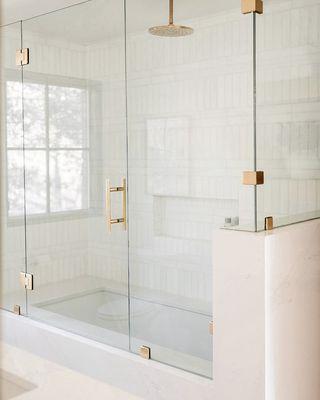 Custom shower with drop in tub wrapped in quartz with custom glass.