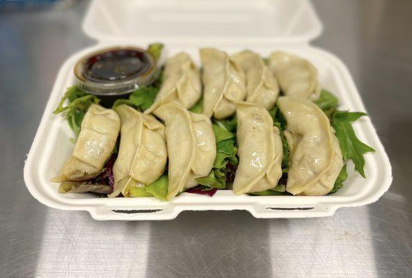 Takeout dumplings with mixed greens in eco-friendly containers