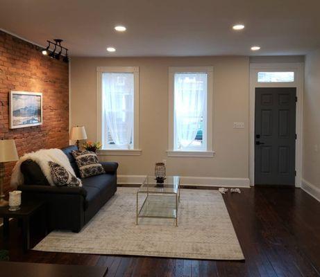 Beautifully remodeled living room in a Lancaster city townhouse - exposed brick hardwood floors and can lighting.