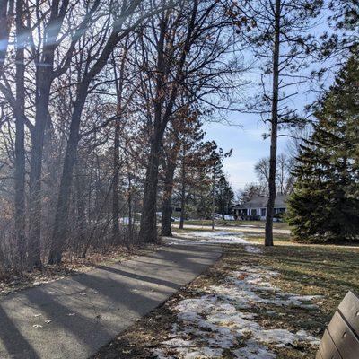 Sample view from a bench of an asphalt pathway that goes partially around the lake.