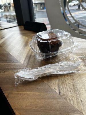 Muffin in plastic packaging with plastic utensils.