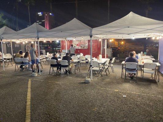 Food truck set up at night.  Nice covered seating with lights. The waiters are very attentive and polite.  The food is outstanding.