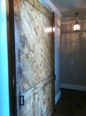 Custom sliding barn door conceals laundry room from hallway in Condominium.