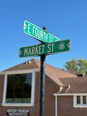 Street sign showing the E. Fourth Street and Market Street intersection with the History Museum in the background