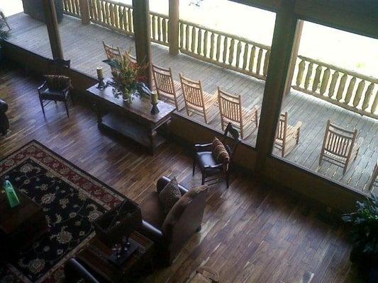 Large windows frame a lake view and showcase rocking chairs on porch.