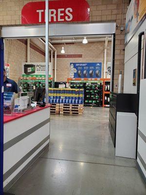 partial view of the tire center desk and background display wiper blades, batteries and tires for install.