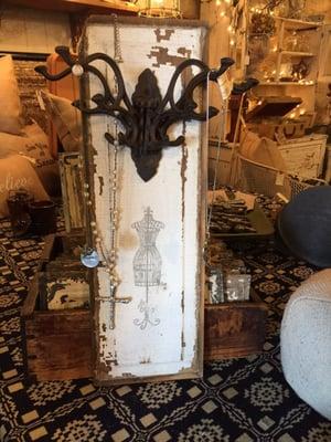 Cast iron 5 way hook on a vintage door panel being used to hang necklaces