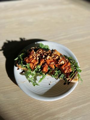 SWEET POTATO & GOAT CHEESE TOAST: sourdough, goat cheese, arugula, maple glazed sweet potato, granola, balsamic glaze, spicy honey